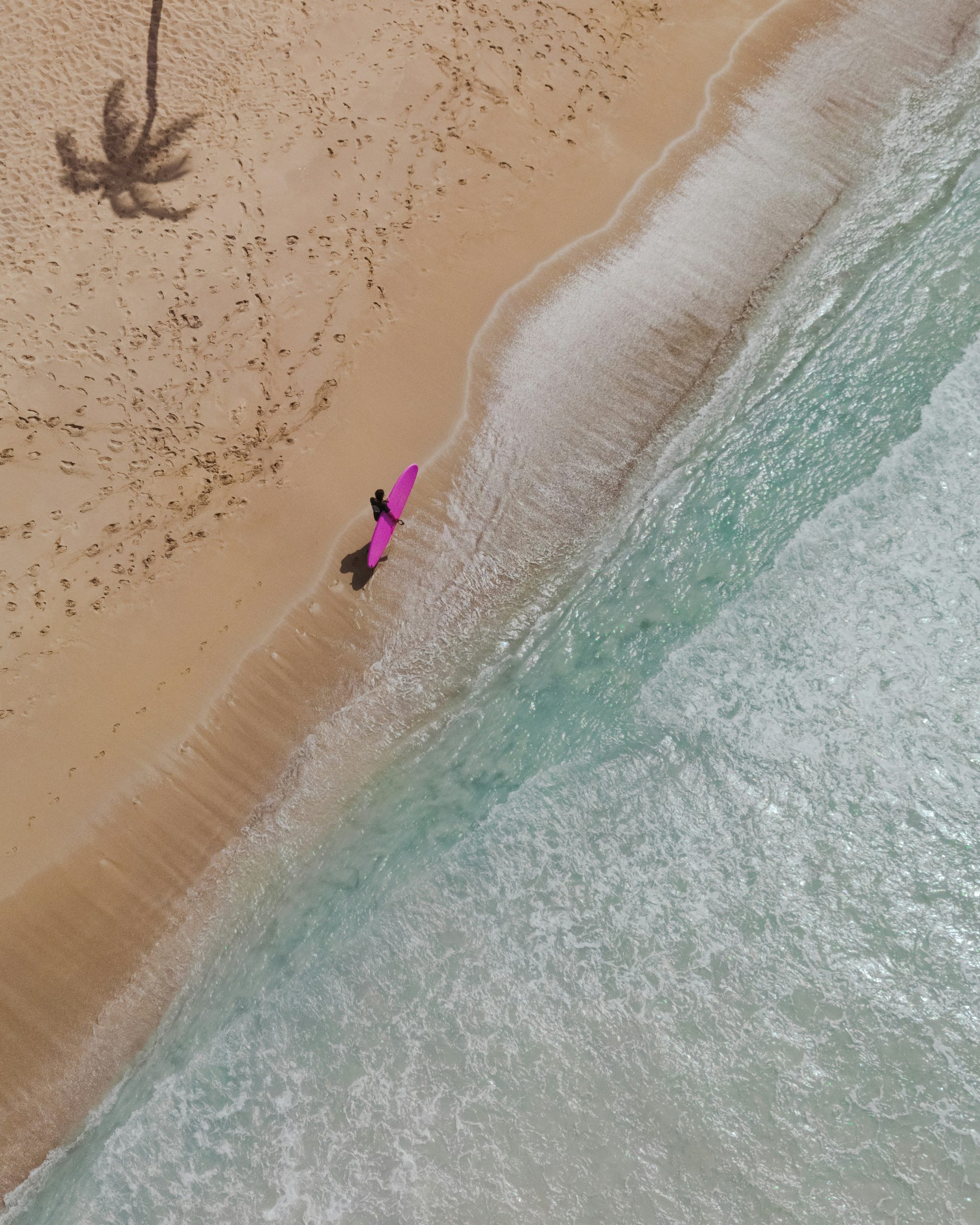 Vista aérea de playa en Punta Cana con surfista y mar Caribe, símbolo del estilo de vida frente al mar y el atractivo para inversión inmobiliaria.
