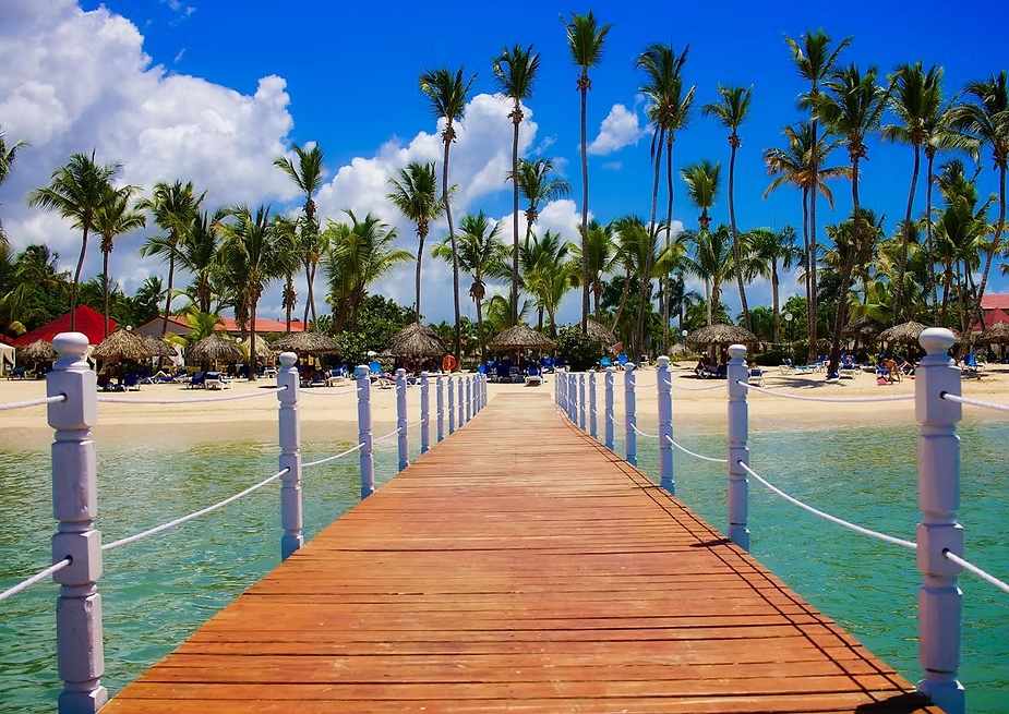 Vista aérea de playa en Punta Cana con palmeras y mar Caribe, símbolo de seguridad, calidad de vida y confianza para inversionistas extranjeros.
