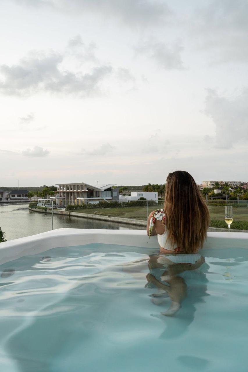 Mujer en piscina de terraza brindando con champán frente a la Marina Cap Cana, imagen de renta corta de ultralujo y estilo de vida premium.