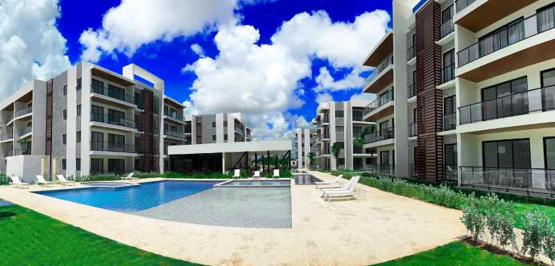 Área social y piscina del proyecto The Towers en Vista Cana, con edificios residenciales de baja altura y amenidades al aire libre.