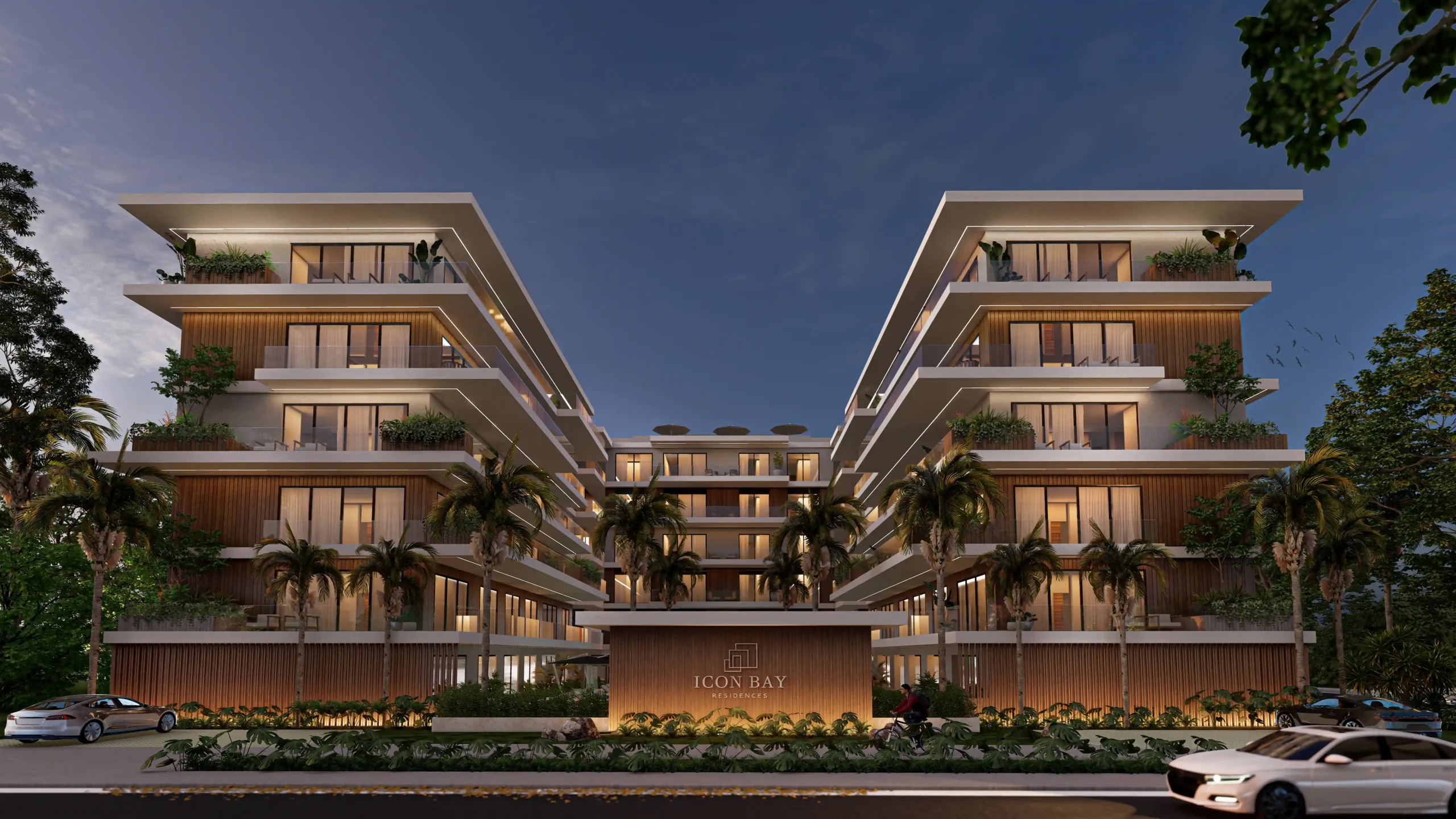 Fachada moderna de Icon Bay en Cap Cana con diseño simétrico, balcones y vegetación tropical iluminada al atardecer
